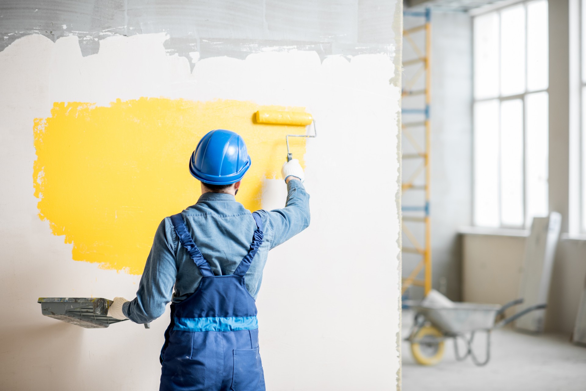 Workman painting wall indoors